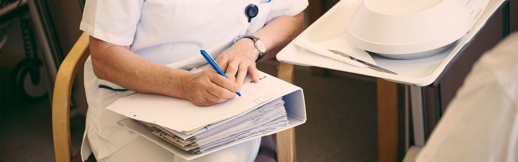 Person mit Ordner auf den Beinen und Stift in der Hand