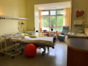 Familienzimmer im Vinzenzkrankenhaus mit Kinder- und Patientenbett, Wickelstation, Sitzball und Sitzgelegenheiten vor dem Fenster.