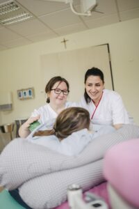 Mutter wird mit Massagebällen von den Hebammen massiert