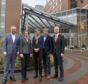 Fünf Personen stehen nebeneinander und schauen in die Kamera.